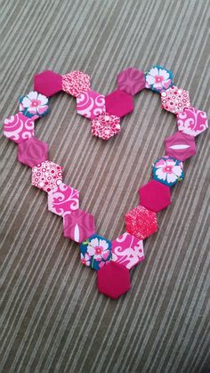 a heart made out of pink and blue flowers on a brown tablecloth with the word love spelled in it