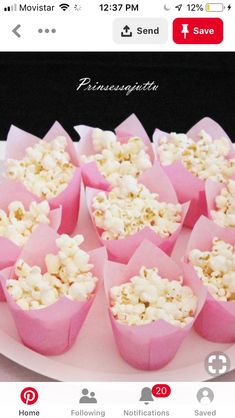 some pink cups filled with popcorn on top of a white plate