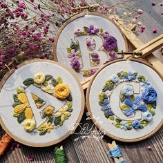 two embroidery hoops with letters and flowers on them