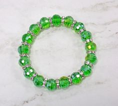 Pretty green color glass beaded stretch bracelet with crystal spacer beads. Each bead is round and all facet cut with a slight aurora borealis finish.  A nice green color fashion piece that is great everyday or for any occasion.   Stretch Bracelet The glass beads are 10 mm  Silver plated crystal spacer beads. Length is 7.5 inches Cheap Green Beaded Bracelets With Oval Beads, Green Round Beaded Bracelets For Party, Green Rondelle Beaded Bracelets With Faceted Beads, Green Stretch Bracelet With Faceted Round Beads, Green Faceted Beads Stretch Bracelet Gift, Green Faceted Beads Stretch Bracelet For Gift, Green Rondelle Bracelets With Faceted Beads, Faceted Green Beaded Bracelets, Green Stretch Bracelet With Faceted Beads For Gift