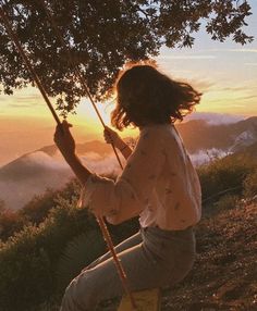 a woman sitting on a swing at sunset