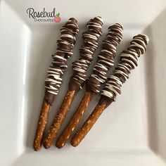 four chocolate covered pretzels on a white plate