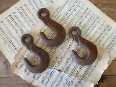 two old cast iron hooks sitting on top of sheet of music with musical notes in the background