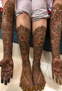 the legs and feet of a woman with henna tattoos on their hands, both covered in intricate designs