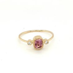 a pink tourmaline and diamond ring on a white background, with the stone in the center