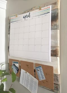 a calendar hanging on a wall next to a potted plant and some notes attached to it