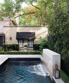 a house with a pool in front of it and trees around the back yard area