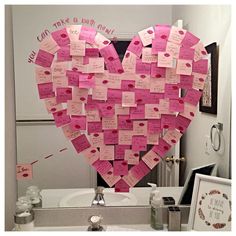 a heart made out of sticky notes on a bathroom counter top next to a mirror