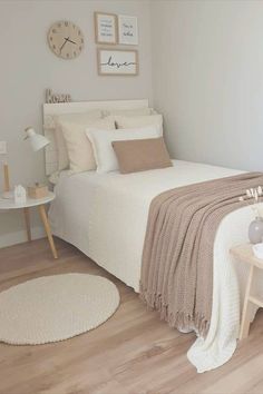 a bedroom with a white bed and beige blankets on top of the bedspread