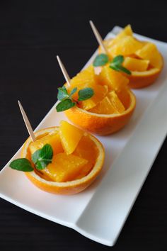 small oranges with toothpicks in them on a white plate