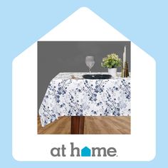 a table covered with a blue and white flowered tablecloth next to a vase filled with flowers