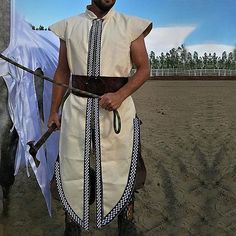 a man standing next to a horse on a dirt field with a white cloth draped around his neck