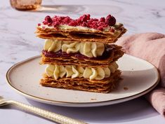 a stack of waffles with bananas and raspberries on top sitting on a plate