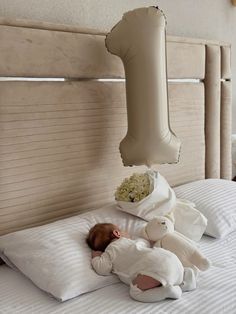 a baby laying on top of a bed next to an inflatable object hanging from the ceiling