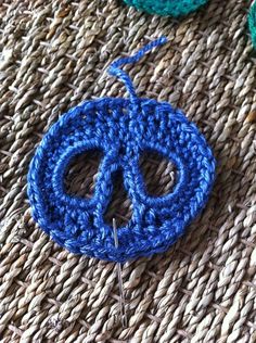 a blue crochet peace sign pin sitting on top of a woven table cloth