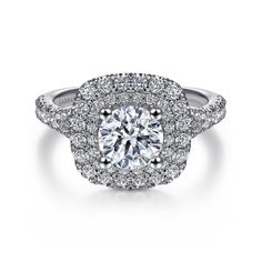 a white gold engagement ring with round diamonds on the sides and halos around it