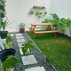 a wooden bench sitting in the middle of a lush green yard next to potted plants