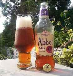 two bottles of alcohol sitting next to each other on top of a table with trees in the background