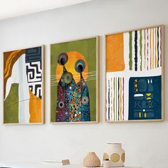 three abstract paintings hang on the wall above a white table with vases and books