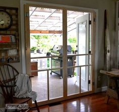 an open glass door leading to a room with a desk and chair in it,