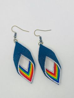 a pair of earrings with multicolored beads hanging from hooks on a white surface