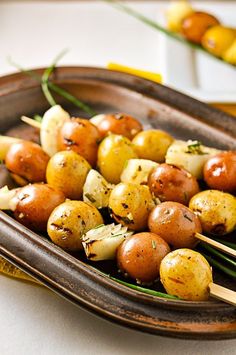 there is a plate with potatoes and skewers on the table next to lemons