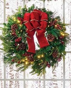 a christmas wreath with red bow and pine cones