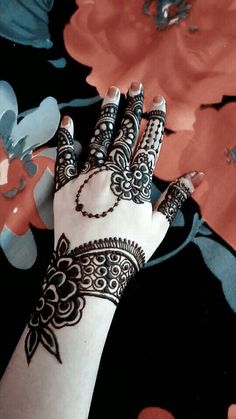 a woman's hand with henna on it and flowers in the back ground