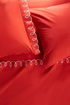 red sheets and pillows with white trim on them