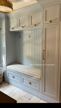 a white kitchen with built in cabinets and a bench