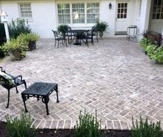 a brick patio with chairs and table in the middle