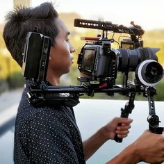 a man holding a video camera in front of his face and looking into the distance