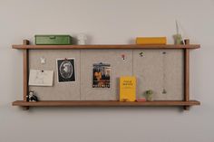 a bulletin board with pictures, books and other items hanging on the wall above it