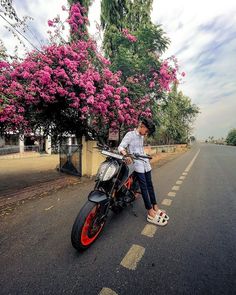 a man is sitting on his motorcycle in the middle of the road with pink flowers