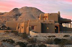 an adobe - style house in the desert with mountains in the background