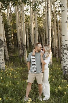 a man and woman are standing in the woods with their arms around each other as they hug