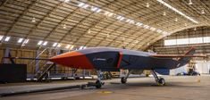 an orange and blue jet sitting inside of a hangar