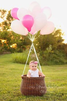 a baby sitting in a basket with balloons