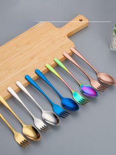 the spoons and forks are lined up on a cutting board