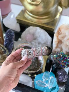 a person holding an object in their hand next to some crystals and other items on a table