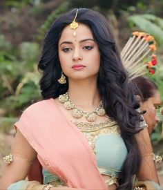 a woman in a sari with long hair and jewelry on her head is looking at the camera