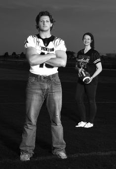 a man and woman are standing in the grass with their arms crossed, looking at the camera