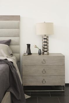 a bedroom with a bed, night stand and lamp on the nightstand next to it