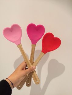 four heart shaped spatulas held up in the air by a person's hand