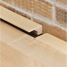 a close up of a wooden bench near a brick wall