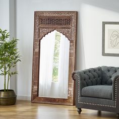 a chair sitting in front of a mirror on the wall next to a potted plant