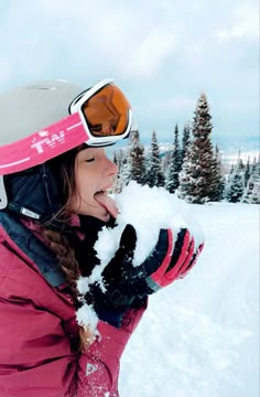 a woman in pink jacket blowing snow with skis on