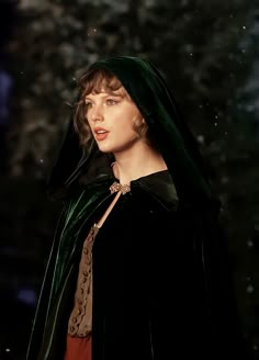 a woman wearing a green cloak and red dress