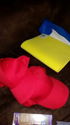 three hats are laying on the floor next to each other, one is red and one is blue