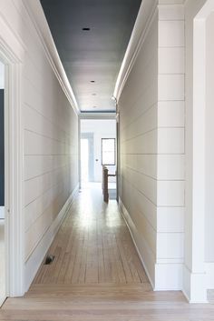 an empty hallway with white walls and wood floors